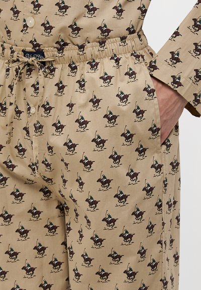 Beige kangast pajama komplekt, millel on korduv muster ratsutajatest. Paindlik elastne vöökoht, lips, nööbiga sulgemine ja küljetaskud.