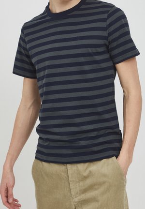 Camiseta de manga corta a rayas en azul marino y gris, hecha de tela suave, con cuello redondo y un sutil logo en el pecho.