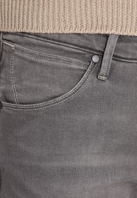 Grå denimjeans med en klassisk femfickdesign, knappstängning och kontrasterande sömmar längs fickorna och sömmarna.