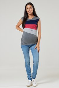 Maternity top with cap sleeves, featuring color block design in navy, red, and gray. Paired with light blue skinny jeans and white sneakers.
