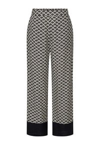 Pantalons à motif crème avec un design géométrique noir, présentant une coupe droite et des jambes larges, terminés par un revers noir uni.