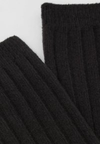Czarna ribbed dzianina prezentująca miękką, teksturowaną powierzchnię z pionowymi liniami. Materiał jest gruby i ciepły, idealny na zimowe ubrania.