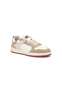 Baskets basses avec un dessus en cuir suédé beige et cuir blanc, accent rouge, bout rond et semelle en caoutchouc.