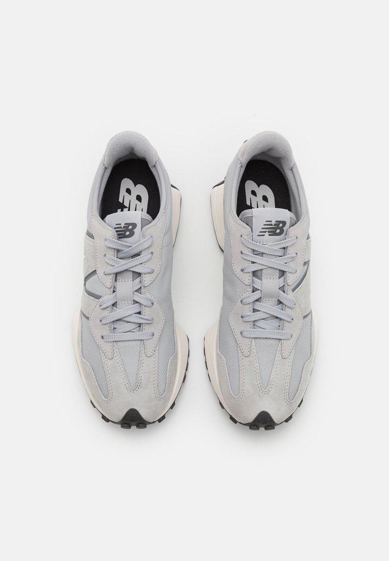 Hellgraue Sneakers aus einer Mischung von Wildleder und Mesh-Materialien, stromlinienförmiges Design, flache Schnürsenkel und eine dicke schwarz-weiße Sohle.
