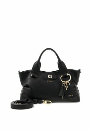 Schwarze Guess-Handtasche mit zwei Griffen, goldenem Logo und Charms sowie einem abnehmbaren Schulterriemen, der neben der Tasche liegt.