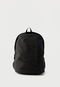 Μαύρο σακίδιο πλάτης με λεία, ματ επιφάνεια. Διαθέτει λαβή στο πάνω μέρος, επενδυμένους ιμάντες ώμου και πλαϊνές τσέπες με φερμουάρ.
