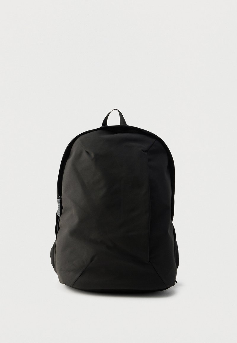 Μαύρο σακίδιο πλάτης με λεία, ματ επιφάνεια. Διαθέτει λαβή στο πάνω μέρος, επενδυμένους ιμάντες ώμου και πλαϊνές τσέπες με φερμουάρ.