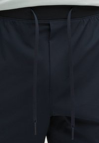 Pantalones cortos deportivos de color azul marino con una cinturilla elástica, que presentan cordones negros y una textura de tela suave y ligera.