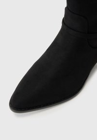 Nurka mustaga sädemega ankle boot, mis on valmistatud pehmest sametist, sujuva tekstuuriga ja minimaalsete õmblusdetailidega, millel on sale, voolujooneline disain.