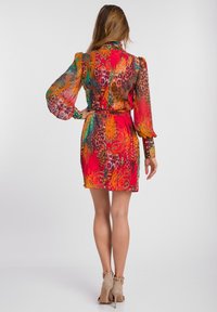 Färggklad sidenklänning med långa puffärmar, prydd med djurmotiv i röd, orange och grön. Har en cinchad midja och en bälte detalj på baksidan.