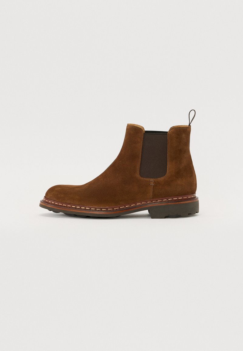 Zemākās uzņēmuma suede brūnās Chelsea zābaki ar elastīgām sānu daļām un cilpu. Iezīmē izturīgu gumijas zoli ar šuvju detaļām un noapaļotu pirkstu.