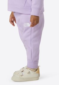 Vaaleanliilat collegehousut, joissa on joustava vyötärönauha ja pieni valkoinen logo. Yhdistettyyn valkoisiin kenkiin, joissa on tarrakiinnitys.