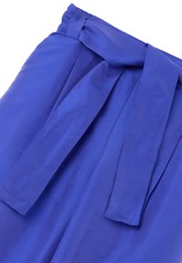 Blauwe, loszittende broek gemaakt van een zachte stof. Heeft een brede tailleband met een afneembare riem en zachte plooien aan de voorkant.