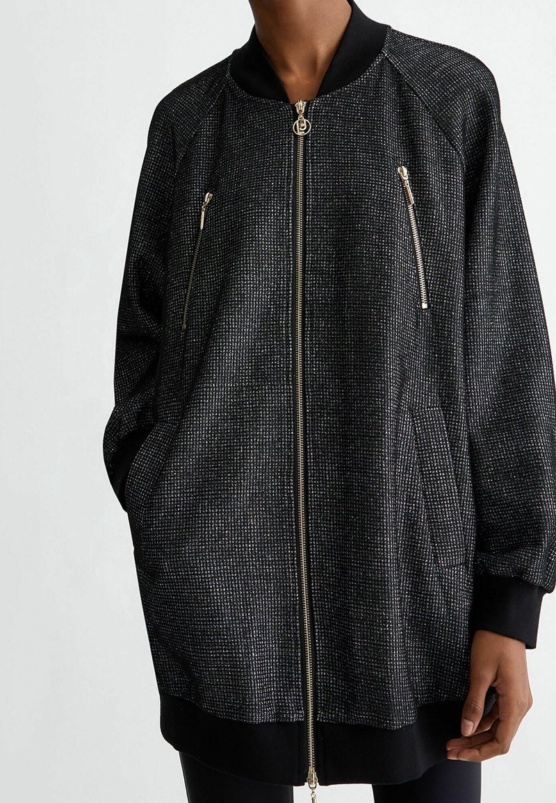 Giacca bomber nera con un effetto metallico testurizzato. Presenta tasche con zip e un colletto a costine. Vestibilità semplice e rilassata con maniche lunghe.