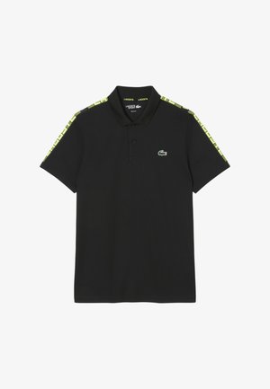 Camisa polo negra con un cuello clásico, que presenta acentos en verde y amarillo con un patrón en los hombros y un pequeño logo en el pecho.
