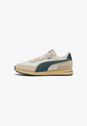 Sneakers beige e verde scuro con una tomaia in suede e tessuto, suola testurizzata e lacci bianchi. Presentano un logo Puma sul lato.