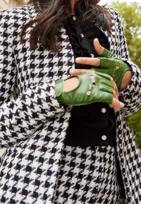 Sort-hvid houndstooth-mønstret blazer med matchende bukser; model iført grønne læder fingerløse handsker med huller og struktureret finish.