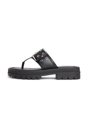 Fekete, vastag talpú szandál vastag pánttal, ezüst csattal és lábujjközi részlettel, oldalán egy kis piros, fehér és kék logóval.