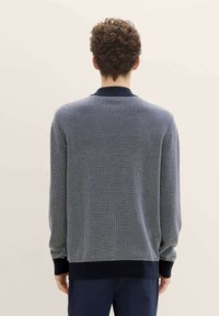 Gebreide navy trui met een textuurpatroon, voorzien van een geribde kraag en manchetten. Het ontwerp heeft een getailleerde pasvorm met lange mouwen.