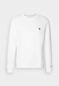Sweat-shirt blanc à col rond avec manches longues, petit logo noir "cK" sur le côté gauche de la poitrine et texte "Calvin Klein" sur le poignet de la manche gauche.