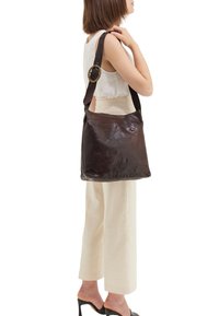 Borsa a tracolla in pelle marrone con una texture liscia, una maniglia larga con un'accoppiatura rotonda in oro e una dimensione moderata per il trasporto a spalla.