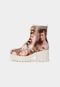 Lace-up enkelboot met een glanzend oppervlak met een geschilderd ontwerp van gezichten. Het heeft een chunky witte platform en gedetailleerde stiksels.
