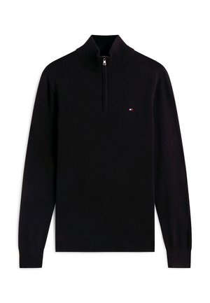 Melnā garroku džemperis ar ceturkšņa rāvējslēdzēju un mazu sarkanu, baltu un zilu taisnstūrveida logotipu uz krūtīm.