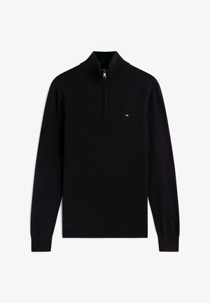 Melnā garroku džemperis ar ceturkšņa rāvējslēdzēju un mazu sarkanu, baltu un zilu taisnstūrveida logotipu uz krūtīm.