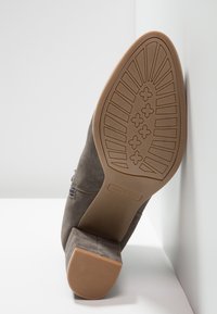 Botte en daim avec talon bloc, motif de la semelle comprenant des formes rectangulaires et croisées, taille 37, nom de la marque Anna Field sur la semelle.