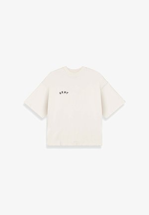 T-shirt oversize beige chiaro realizzata in cotone, con maniche corte e un piccolo logo nero "GRNY" sul lato sinistro.