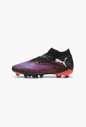 Botas de fútbol negras con una parte superior texturizada que presenta franjas en degradado morado y rojo, diseño bajo y tacos prominentes en morado y naranja.