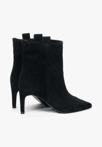 Czarne zamszowe botki za kostkę z szpiczastym noskiem i 3-calowym obcasem stilettos. Wyposażone w pętle z tyłu dla łatwego zakładania. Gładka tekstura.