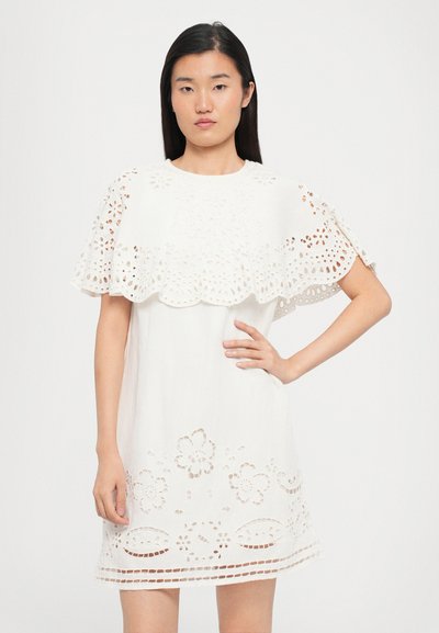 Rochie albă din dantelă cu modele florale tăiate intricate, mâneci ondulate și o croială lejeră. Textură netedă cu un siluetă casual.