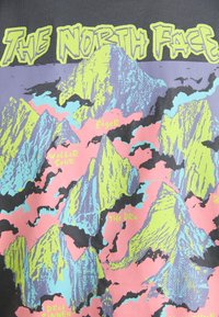 Grafisk t-shirt med et multifarvet bjergprint i pink, blå og neon grøn, med "The North Face" logoet tydeligt placeret øverst.