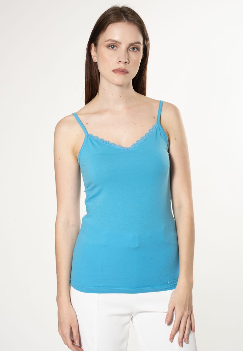 Lichtblauw tanktop met dunne bandjes en schulp kantaccenten langs de halslijn. Gemaakt van zachte, rekbare stof.