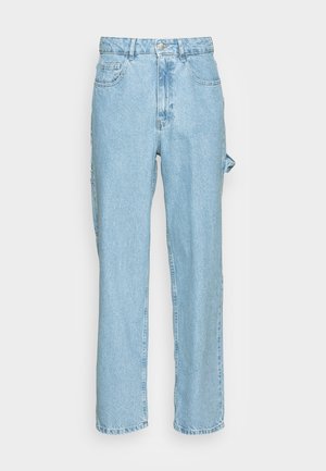 Jean de charpentier en denim bleu clair avec jambes droites, poches avant et arrière, passants de ceinture, et une boucle d'outil latérale sur la jambe droite.