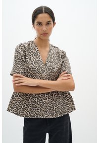 Blůza s krátkým rukávem a potiskem v leopardím vzoru, s výstřihem do V, vyrobená z měkké tkaniny, má volný střih a na ramenou má nařasení.