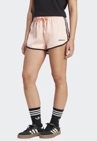 Světle růžové sportovní šortky s černým lemováním, elastickým pasem se stahovací šňůrkou a logem Adidas na levé nohavici.