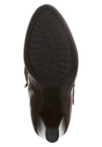 Suela de bota de cuero marrón con una suela exterior de goma negra texturizada, que presenta un tacón en ángulo y un patrón de relieve distintivo para mayor tracción.