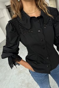 Black button-up shirt with scalloped collar, floral embroidery on sleeves, and lace accents. Made of smooth fabric with a fitted design.