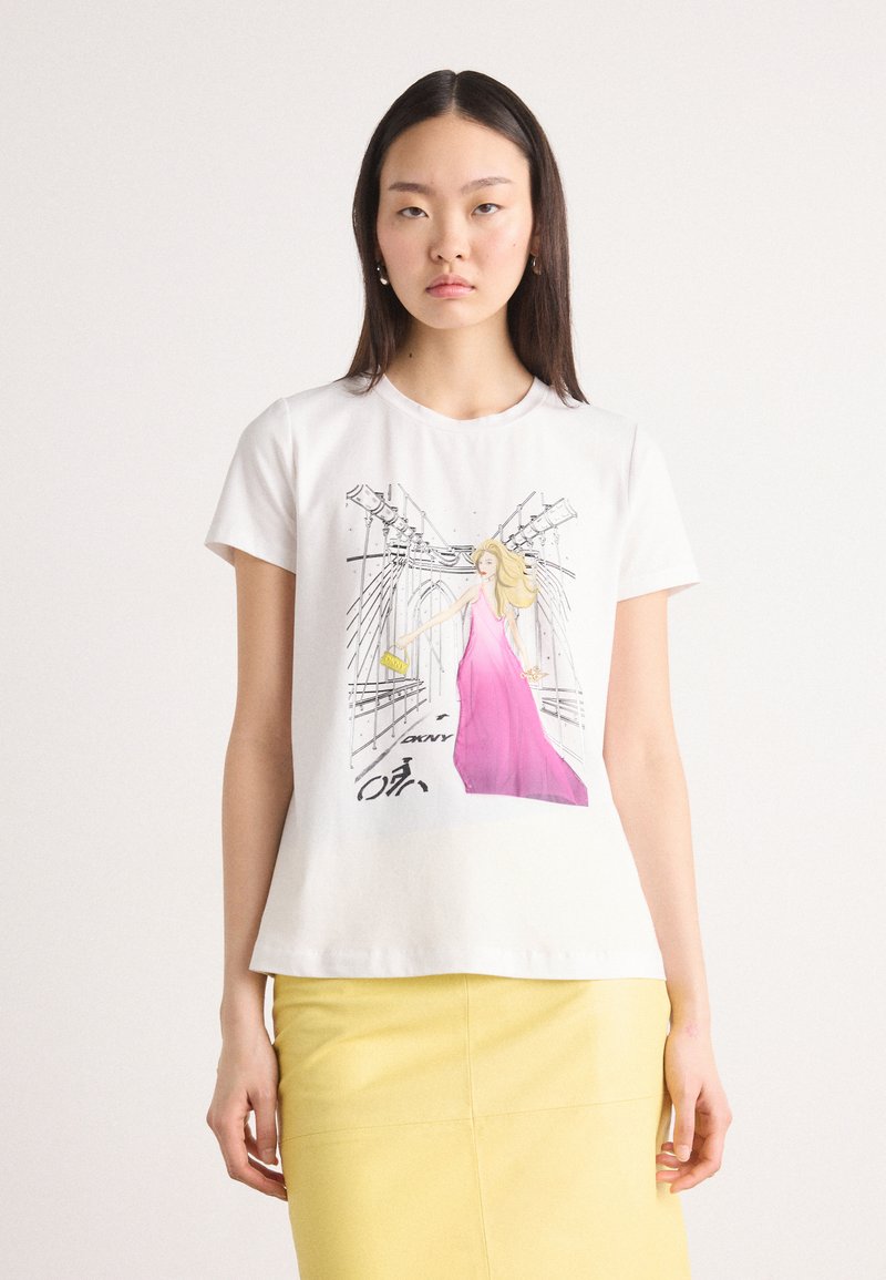 White cotton t-shirt featuring a graphic print of a woman in a pink dress, with a city backdrop and “DKNY” text. Short sleeves, crew neck.
