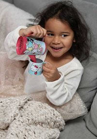 Kaksi värikästä mukia esittelee sarjakuvahahmoja. Vaaleanpunaisessa mukissa on kirkas kuvio, ja sinisessä mukissa on Hello Kitty -grafiikka. Neulottu viltti on näkyvissä.