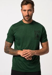 Zelené tričko s krátkým rukávem vyrobené z texturované látky. Na levé části hrudi má černý grafický design, který zobrazuje horu a text.