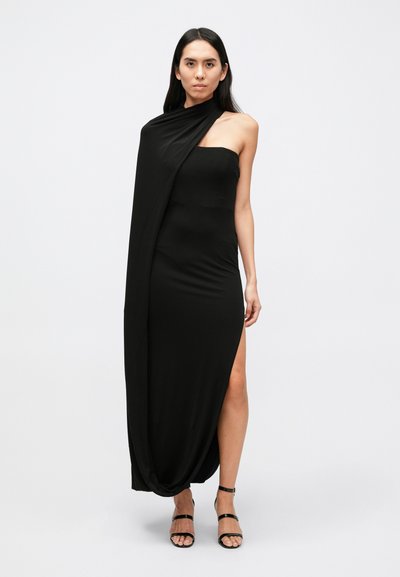 Schwarzes trägerloses Kleid aus dehnbarem Stoff, mit figurbetontem Schnitt, seitlichem Schlitz und drapiertem Detail an der Schulter für zusätzliche Dimension.