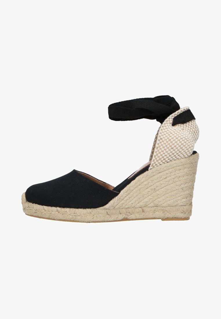 Espadrille compensée en tissu noir avec semelle en jute tressée, renfort de talon à carreaux et bride de cheville noire sur fond blanc.