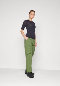 Navy short-sleeve mesh top paired with green cargo pants featuring large pockets and black shoes. Simple design with a fitted silhouette.