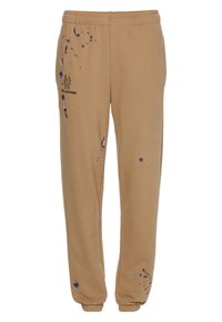 Beige Jogginghosen aus weichem Stoff mit einem Kordelzugbund, elastischen Bündchen und blauen Farbspritzern an der Vorder- und Seitenseite.
