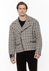 Czarna i biała w kratę kurtka z wełny z klapami, zamkiem błyskawicznym z przodu oraz dwoma kieszeniami na zamek. Skórzane akcenty na mankietach.