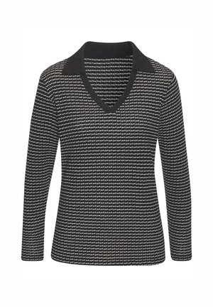 Haut noir à manches longues avec un col en V et un col contrastant, présentant un motif texturé d'éléments graphiques blancs.