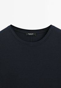 Marineblå bomuld T-shirt med rund halsudskæring, der har en glat tekstur og minimale syningsdetaljer. Mærkeetiket synlig ved halsudskæringen.